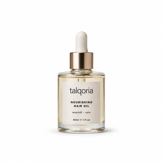 A bottle of talqoria Nourishing Hair Oil with a clear glass body, pale beige oil inside, a metallic gold collar, and a white dropper cap, centered on a white background.