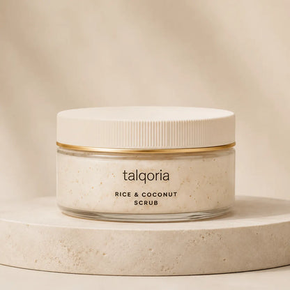 A jar of talqoria Rice & Coconut Scrub with a white lid and gold band, sitting on a round beige stone pedestal against a warm beige background.