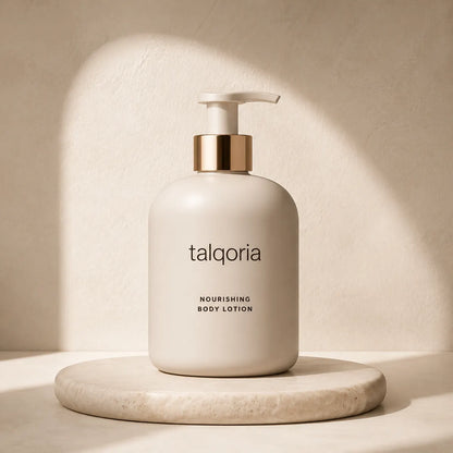 A bottle of talqoria Nourishing Body Lotion in a matte cream color with a gold pump collar, displayed on a round marble coaster against a textured beige wall with soft, artistic shadows.